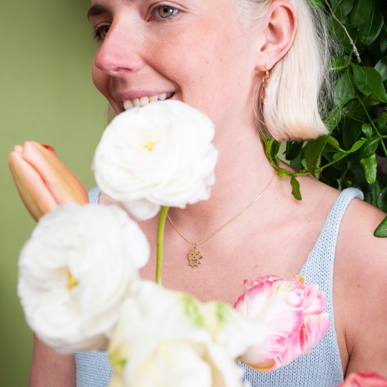 Woman wearing pendant necklace with a spiky irregular shaped charm with a smiley face on