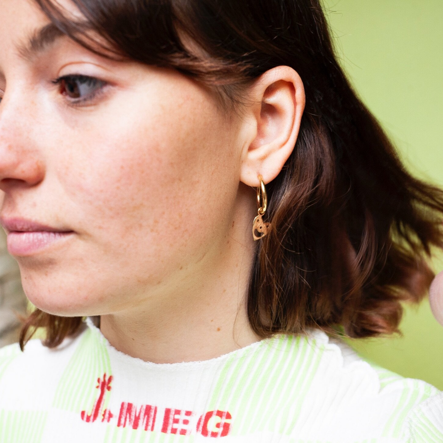 Close up of woman wearing Smiley Heart Hoops earring