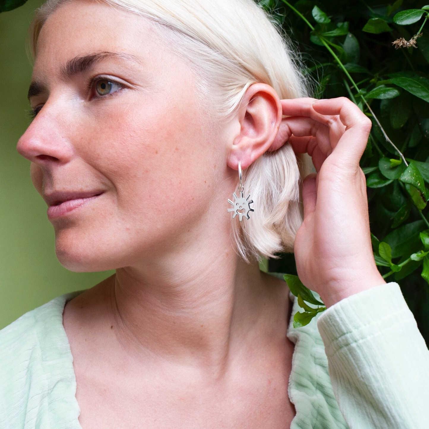 Woman wearing silver Smiley Sun Hoops earring