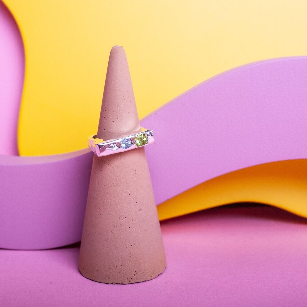 Silver ring with a green gem and a blue gem inset into it