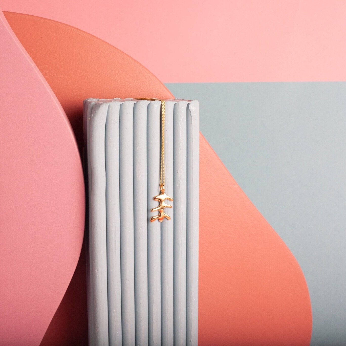 Pendant necklace with a gold abstract shape charm on it