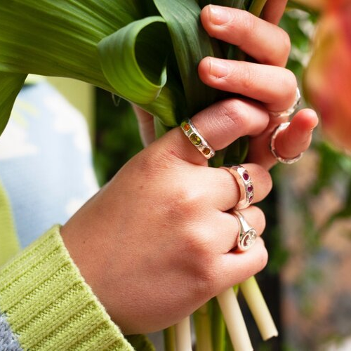 Hand wearing silver rings with 3 pink gems