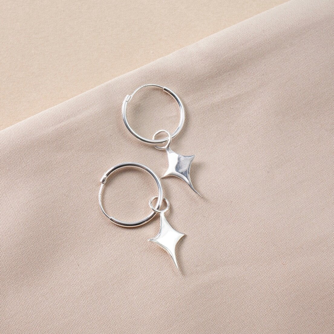 Small silver hoop earrings with a star shaped charm