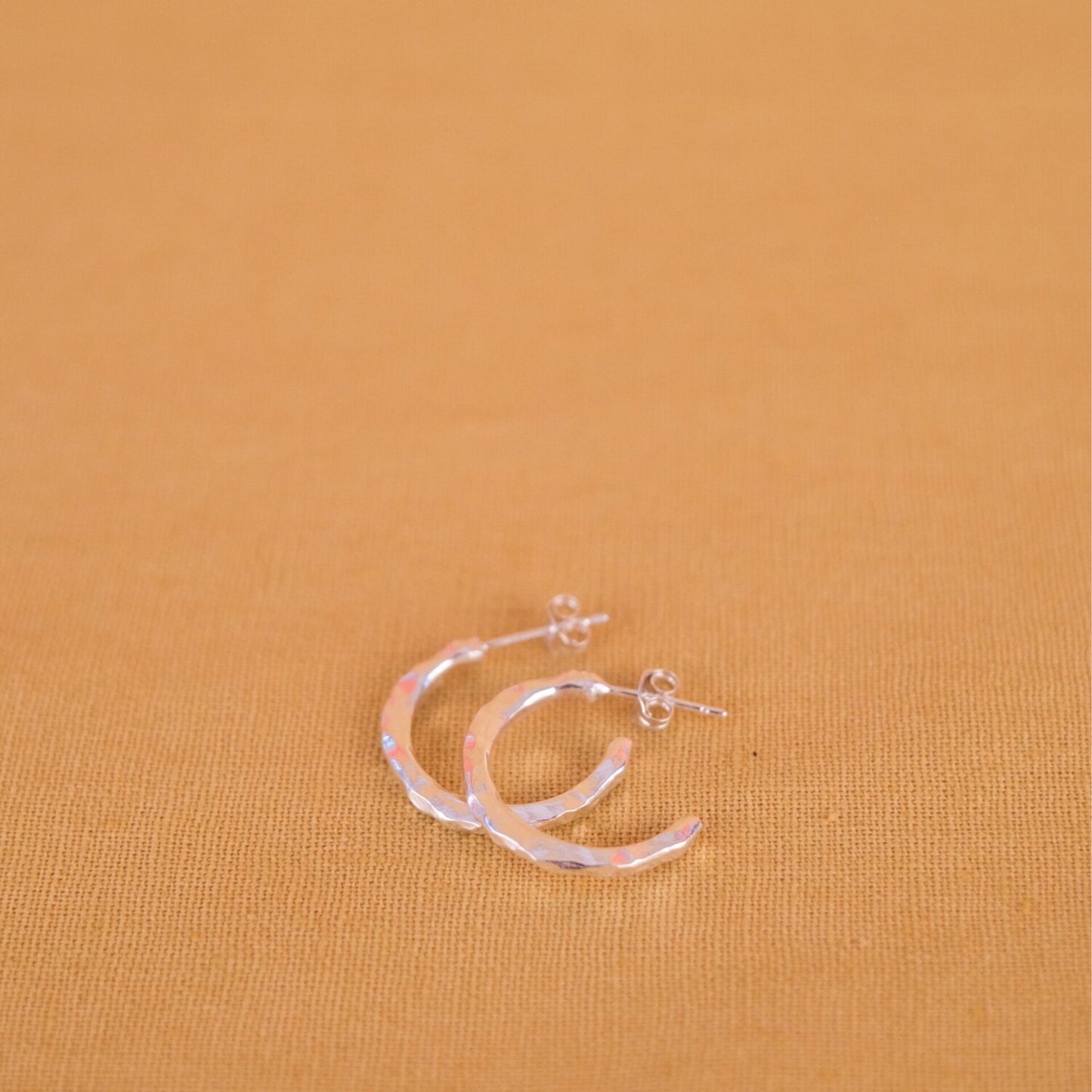 Close up of small silver hoop earrings with a textured surface