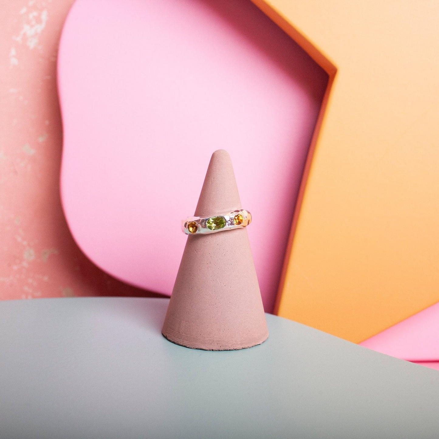 Silver ring with a green gem and yellow gems inset into it