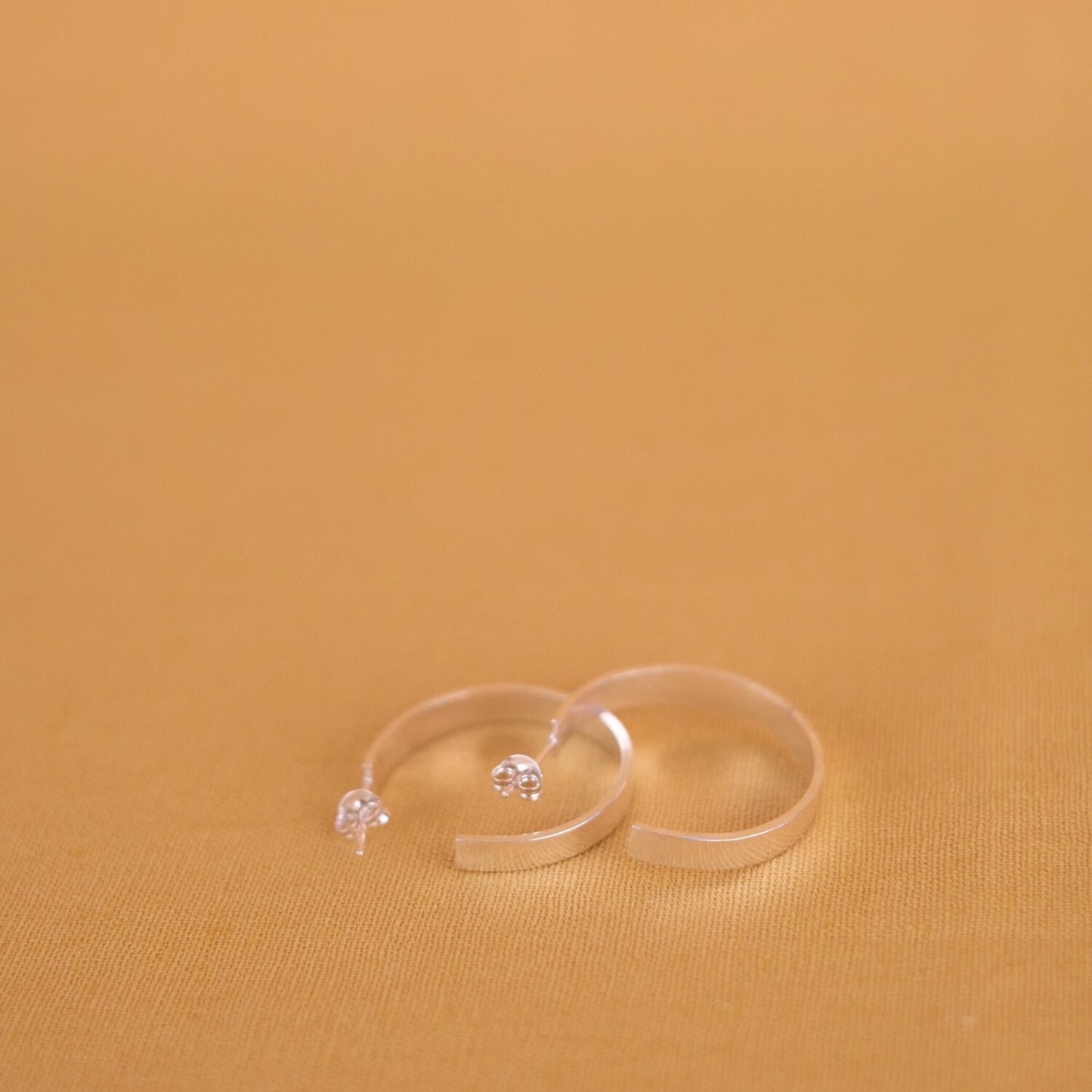 Close up of medium size flat hoop silver earrings