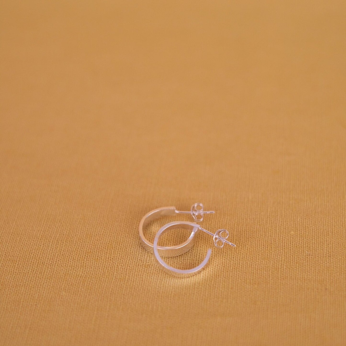 Close up of small, thick silver hoop earrings