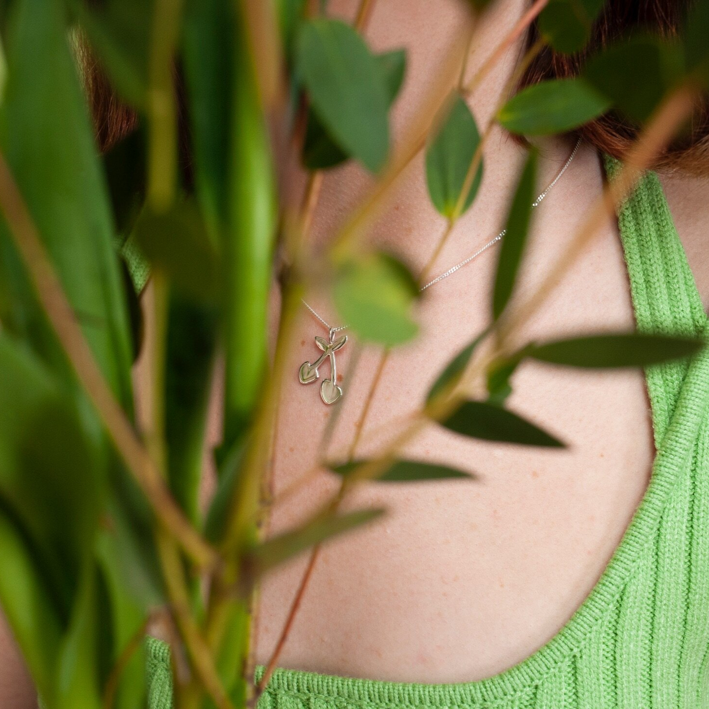 Woman wearing gold pendant necklace with a cherry shaped charm