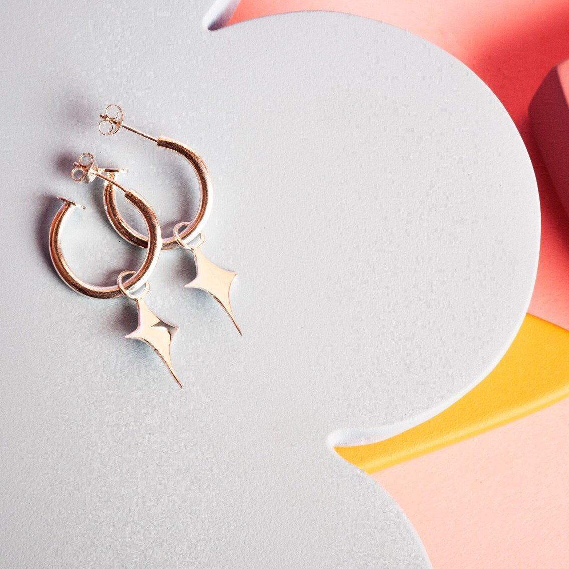 Small gold hoop earrings with a star shaped charm