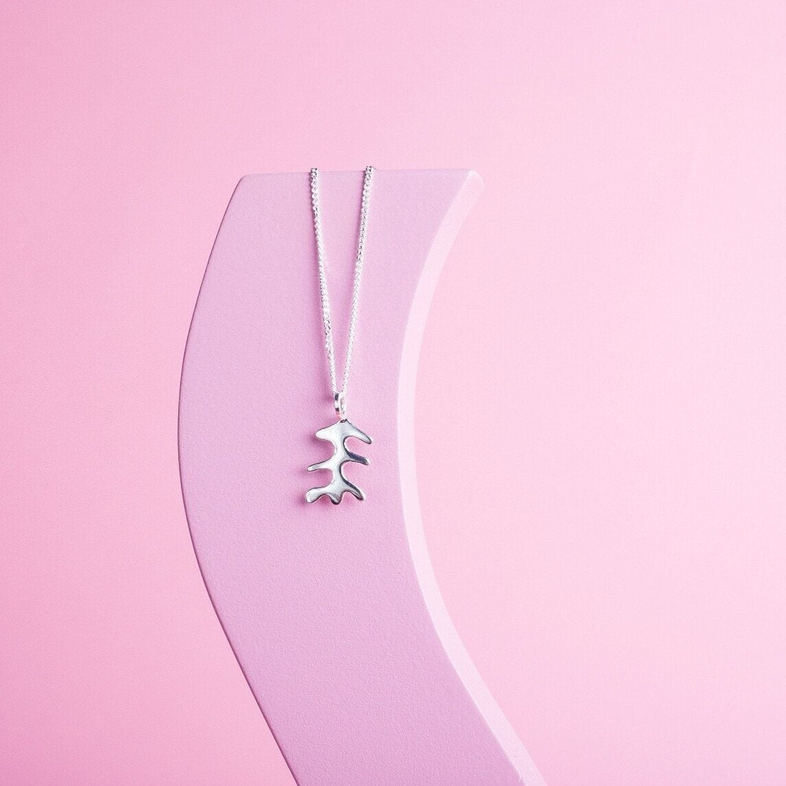 Pendant necklace with a silver abstract shape charm on it