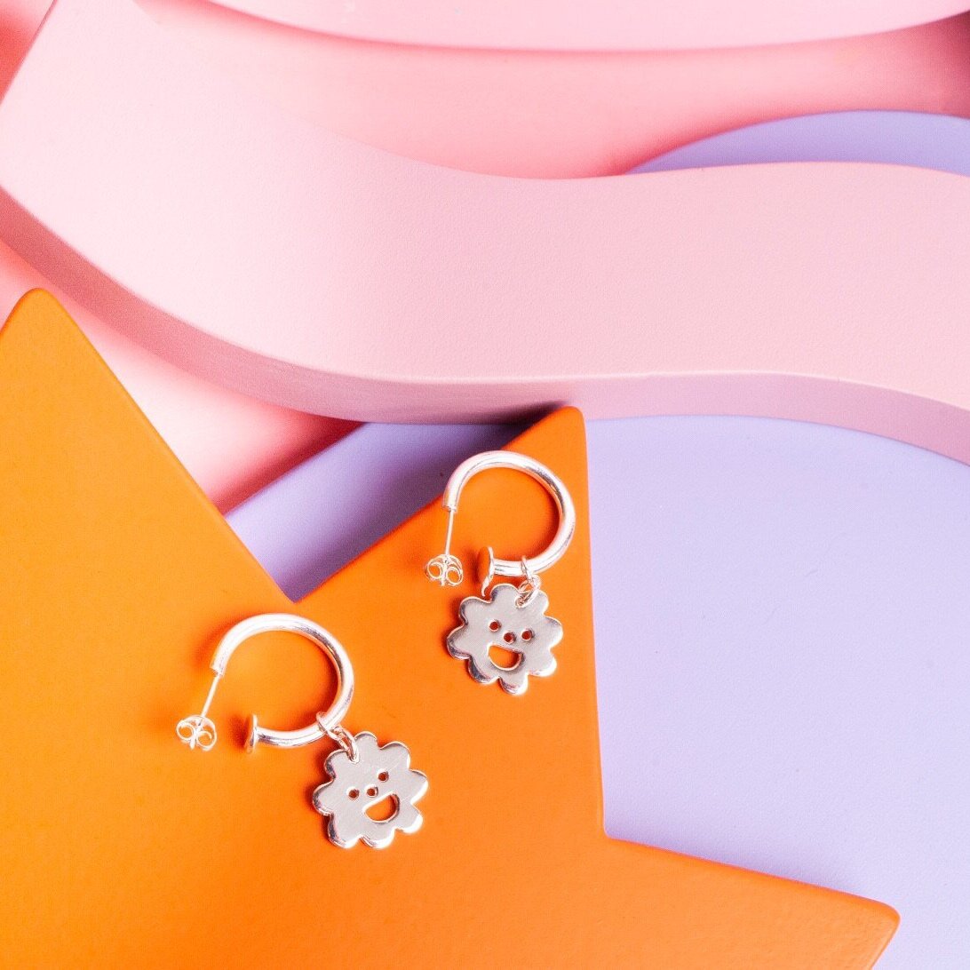 Close up of silver Smiley Flower Hoops earrings