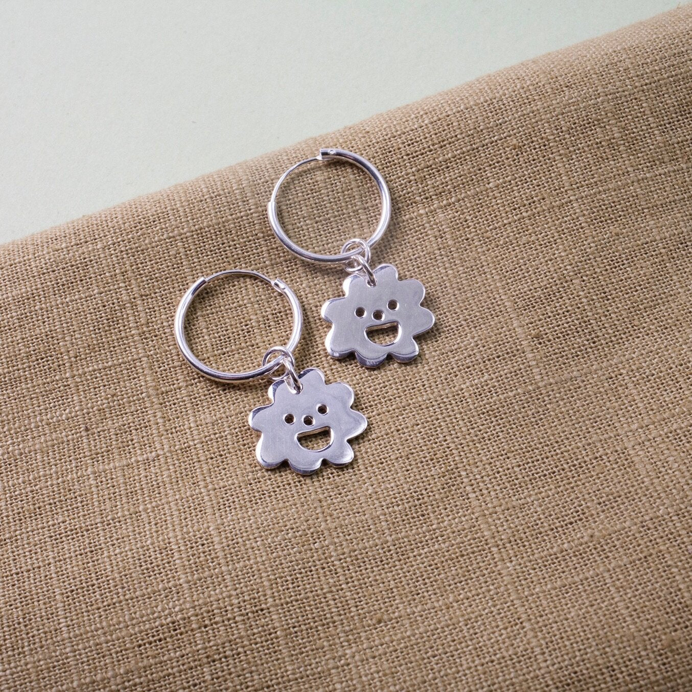 Close up of silver Smiley Flower Hoops earrings
